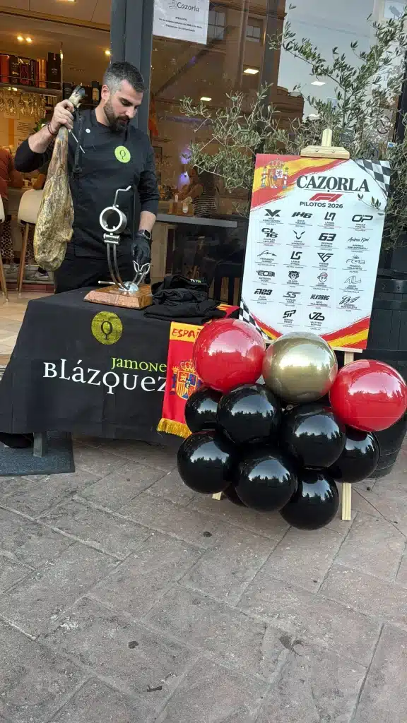 Evento de marca en Madrid con globos negros, rojos y dorados junto a un stand con trofeo